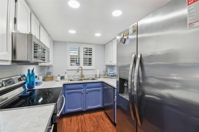 kitchen with a sink, stainless steel appliances, white cabinetry, light countertops, and blue cabinets