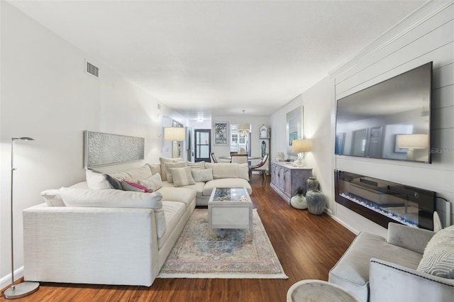 living area featuring baseboards, visible vents, and wood finished floors