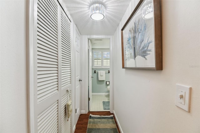 hallway featuring dark wood-style flooring and baseboards