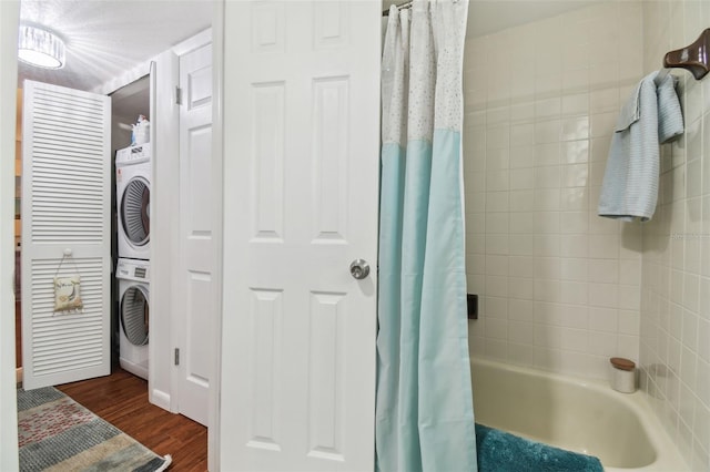 full bath with shower / bath combo with shower curtain, wood finished floors, and stacked washer and dryer