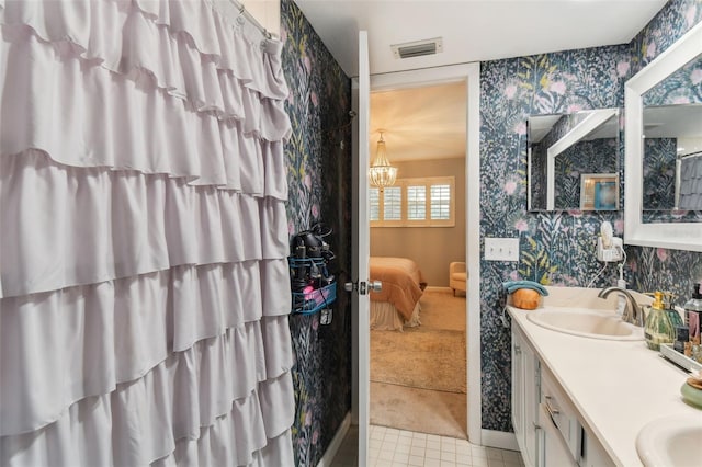 bathroom with a sink, visible vents, baseboards, wallpapered walls, and ensuite bathroom