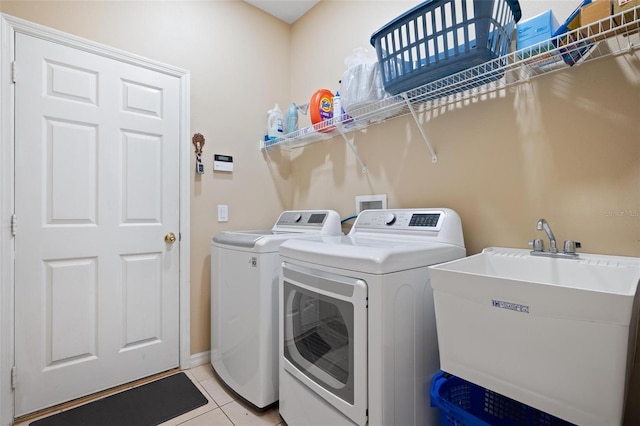 laundry area featuring washer and dryer, light tile patterned flooring, and sink