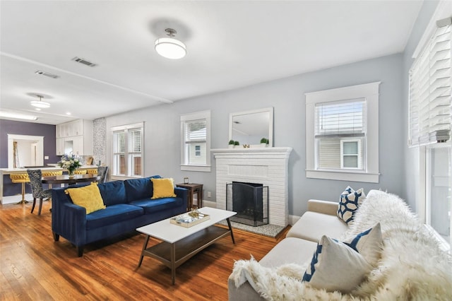 living room with dark hardwood / wood-style flooring and a brick fireplace