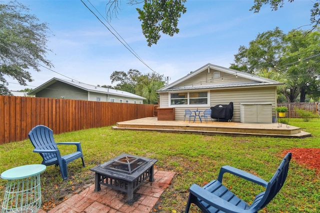 back of house with a deck, a lawn, and an outdoor fire pit