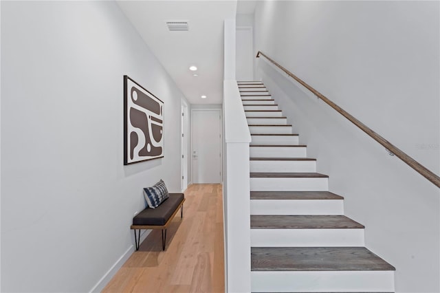 staircase with baseboards, visible vents, wood finished floors, and recessed lighting