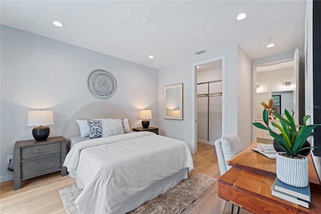 bedroom with light wood-type flooring, visible vents, a walk in closet, and recessed lighting