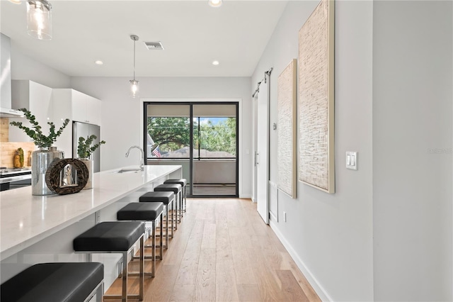 kitchen with white cabinetry, light stone countertops, modern cabinets, a kitchen bar, and decorative light fixtures