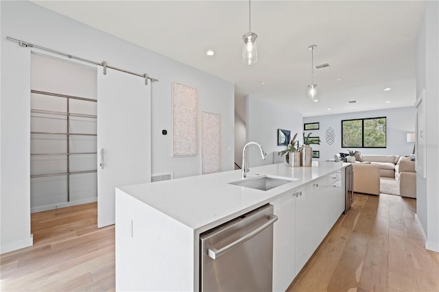 kitchen with a sink, white cabinets, a center island with sink, dishwasher, and decorative light fixtures