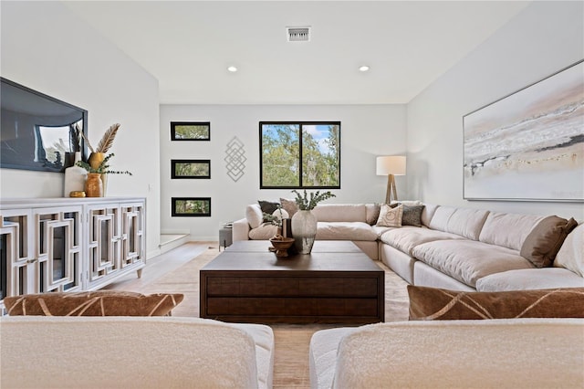 living area with recessed lighting, visible vents, a glass covered fireplace, and light wood-style flooring