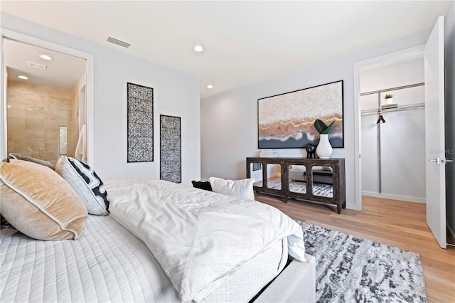 bedroom with a walk in closet, recessed lighting, a closet, visible vents, and wood finished floors