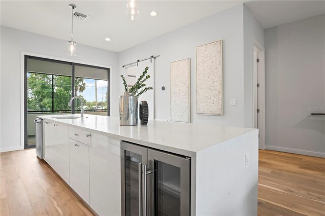532 W Plaza Pl Unit 2, Tampa, FL 33602 - kitchen featuring beverage cooler, a sink, white cabinetry, light wood finished floors, and a kitchen island with sink