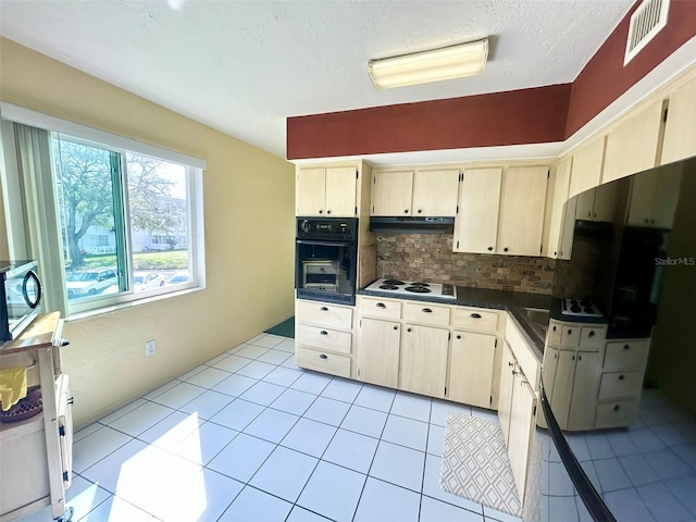 kitchen with light tile patterned floors, black oven, white electric cooktop, light brown cabinetry, and decorative backsplash