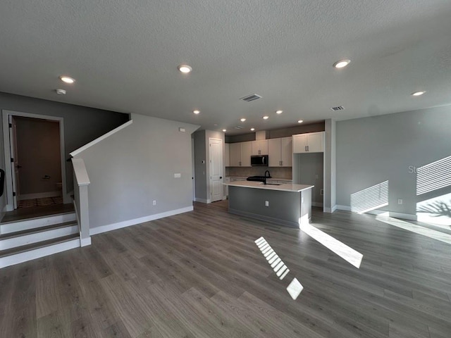 unfurnished living room with hardwood / wood-style floors, sink, and a textured ceiling