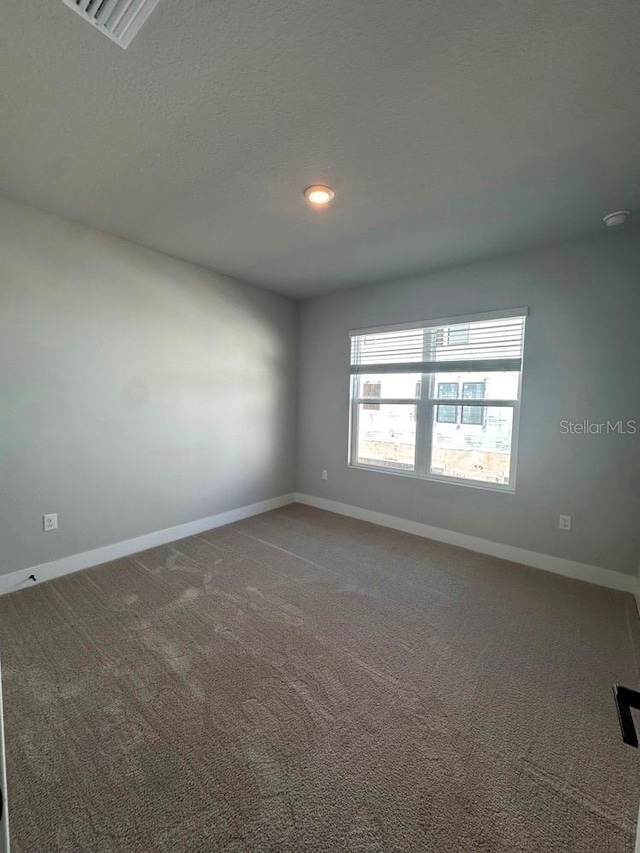 carpeted empty room featuring a textured ceiling