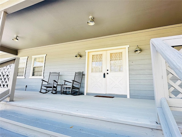 view of exterior entry featuring french doors and a porch