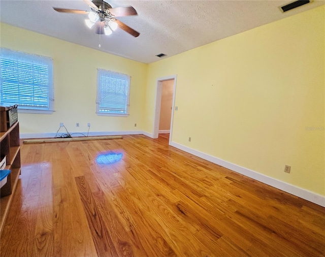 interior space with ceiling fan, a textured ceiling, and light wood-type flooring