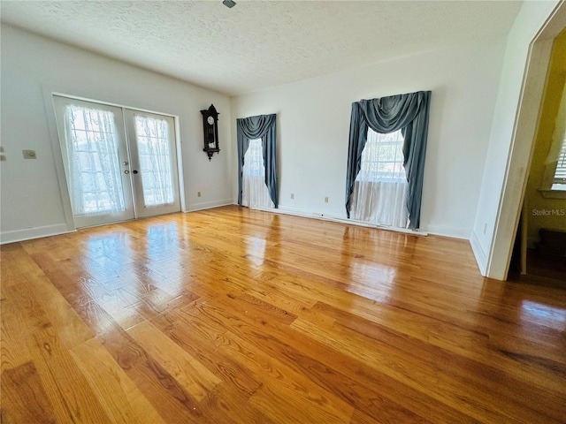 spare room featuring french doors, a textured ceiling, and light wood-type flooring