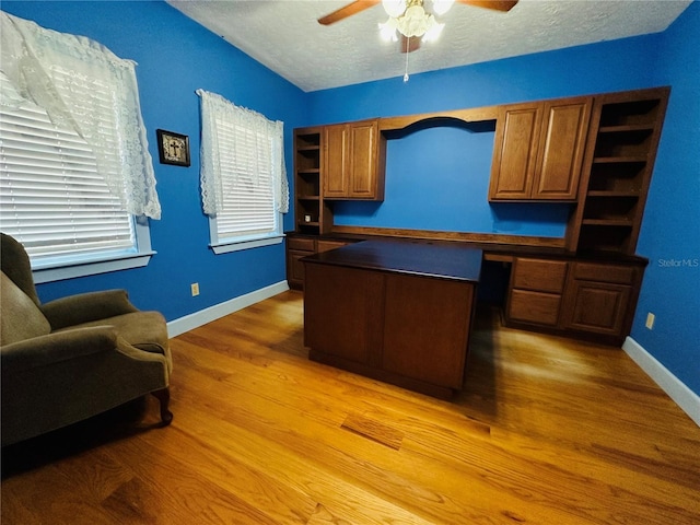 office area with ceiling fan, built in desk, hardwood / wood-style floors, and a textured ceiling