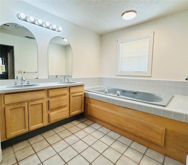 bathroom featuring tiled tub, vanity, tile patterned floors, and a textured ceiling