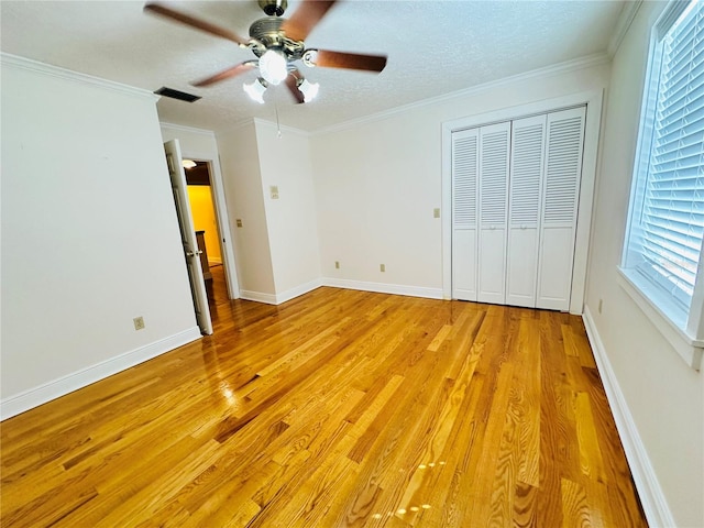 unfurnished bedroom with ceiling fan, ornamental molding, light hardwood / wood-style floors, a textured ceiling, and a closet
