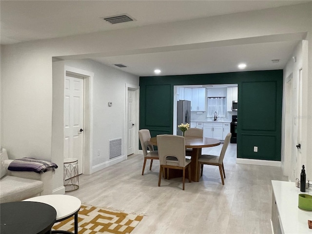 dining area with sink and light hardwood / wood-style floors