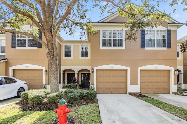 view of front of home with concrete driveway, an attached garage, and stucco siding