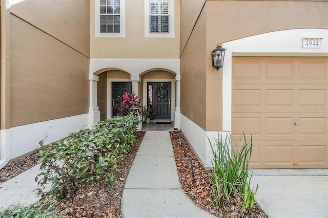 doorway to property featuring a garage and stucco siding