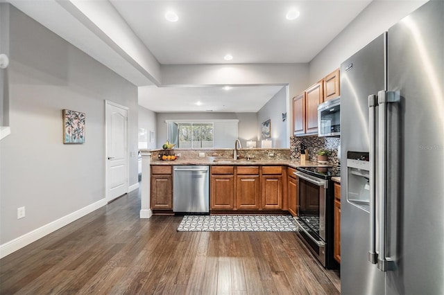 kitchen featuring stainless steel appliances, dark wood-type flooring, a sink, backsplash, and brown cabinets