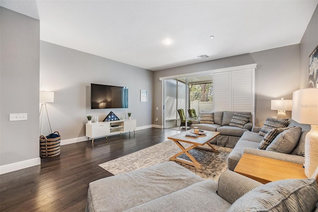 living area with dark wood-type flooring, visible vents, and baseboards