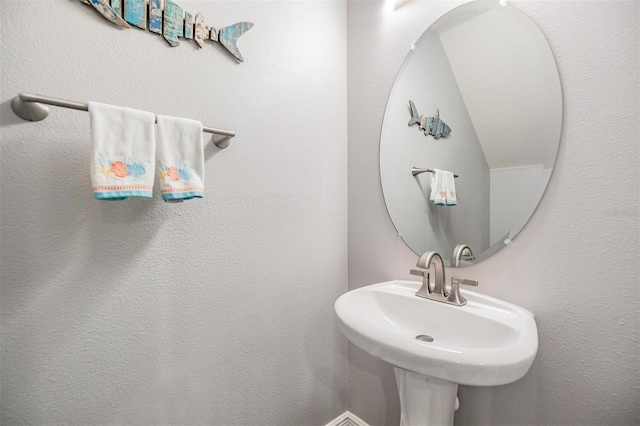 bathroom featuring a textured wall and a sink