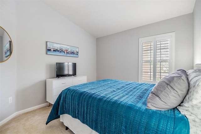 bedroom with lofted ceiling, light carpet, and baseboards