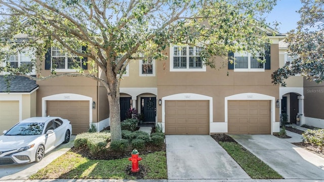 view of property featuring a garage, driveway, and stucco siding