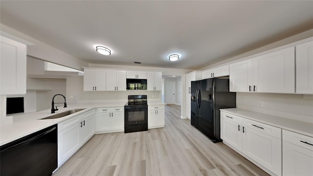 kitchen featuring sink, black appliances, light hardwood / wood-style floors, and white cabinets