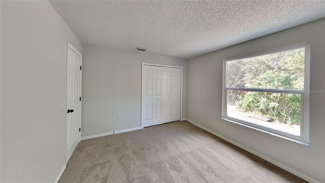 unfurnished bedroom with light colored carpet, a closet, and a textured ceiling