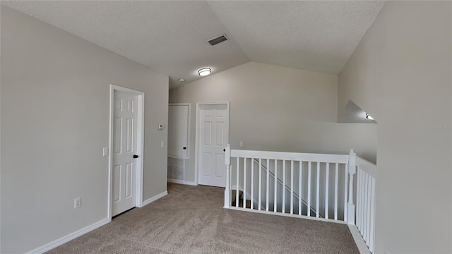 interior space featuring carpet floors, vaulted ceiling, and a textured ceiling