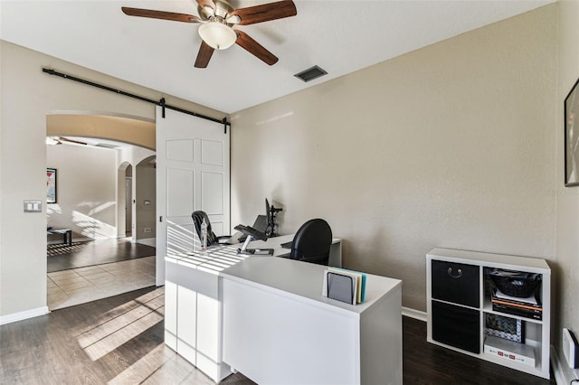 home office with visible vents, arched walkways, baseboards, dark wood-style floors, and ceiling fan