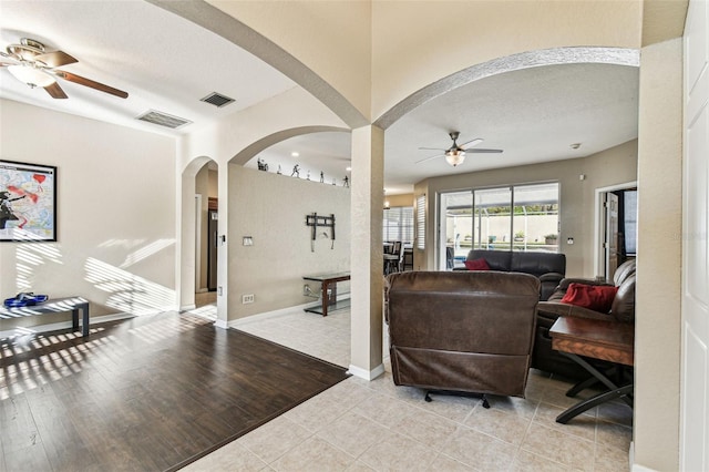 living area featuring ceiling fan, visible vents, and baseboards