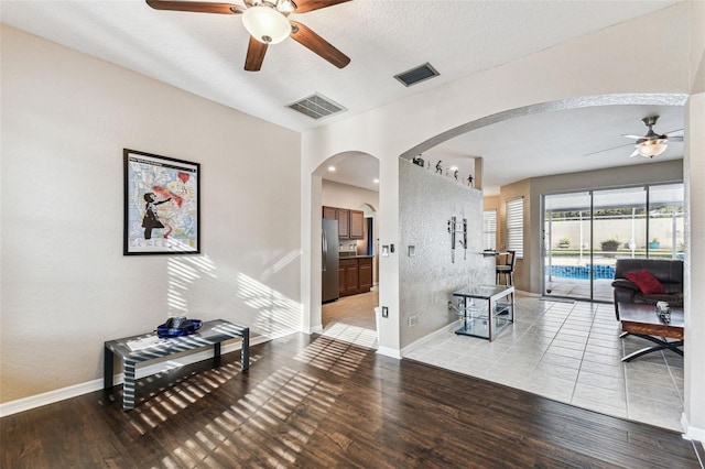 interior space with arched walkways, wood finished floors, visible vents, and baseboards