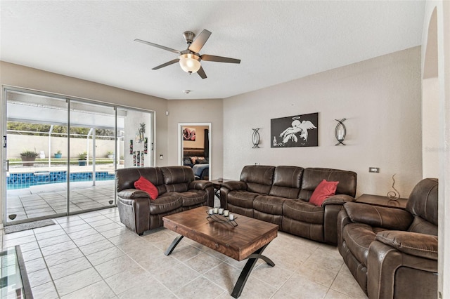 living room featuring ceiling fan, a textured ceiling, and light tile patterned floors