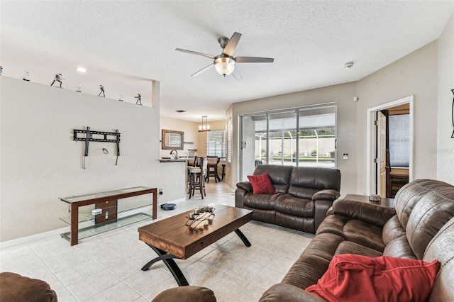 living area featuring light tile patterned floors, ceiling fan, baseboards, and a textured ceiling