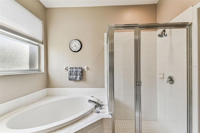 full bathroom with a stall shower, a bath, and a textured wall