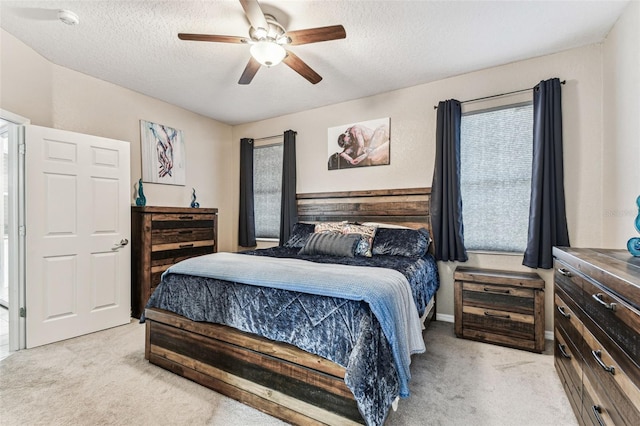 bedroom featuring a ceiling fan, light colored carpet, and a textured ceiling