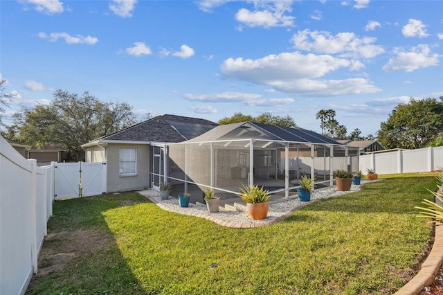 rear view of house with a fenced backyard, a lanai, a gate, a yard, and stucco siding