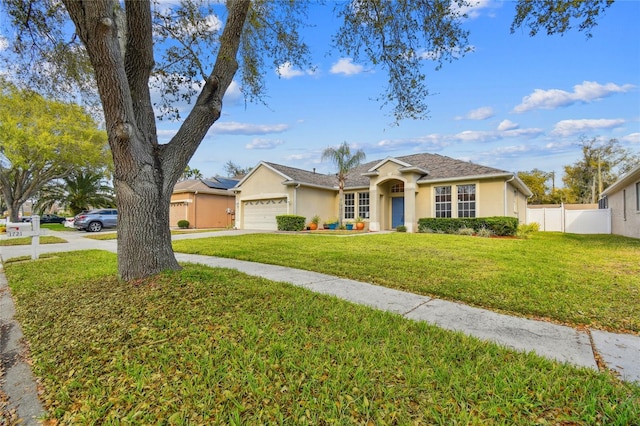 single story home with stucco siding, concrete driveway, a front yard, fence, and a garage