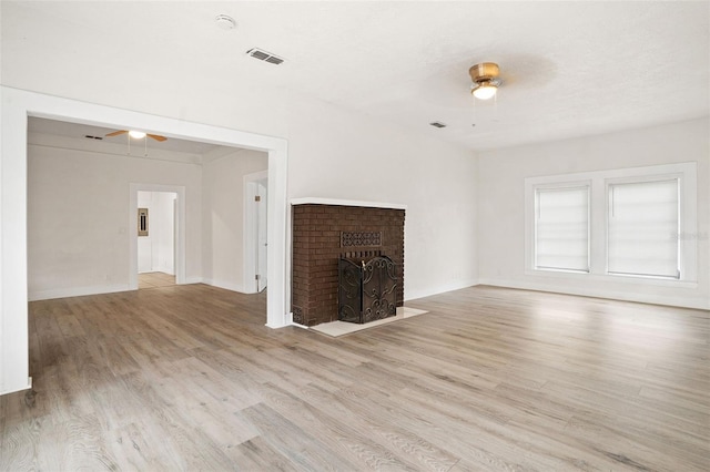 unfurnished living room with ceiling fan, light hardwood / wood-style floors, and a brick fireplace