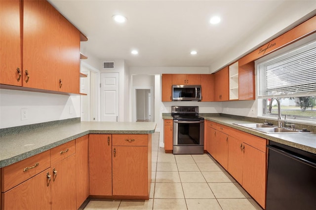 kitchen with appliances with stainless steel finishes, sink, light tile patterned floors, and kitchen peninsula