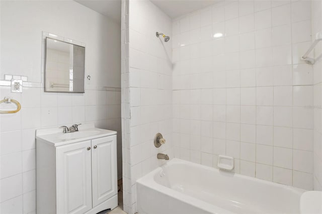 bathroom with tiled shower / bath, vanity, and tile walls