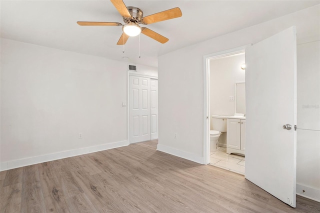 unfurnished bedroom featuring ensuite bathroom, ceiling fan, and light wood-type flooring