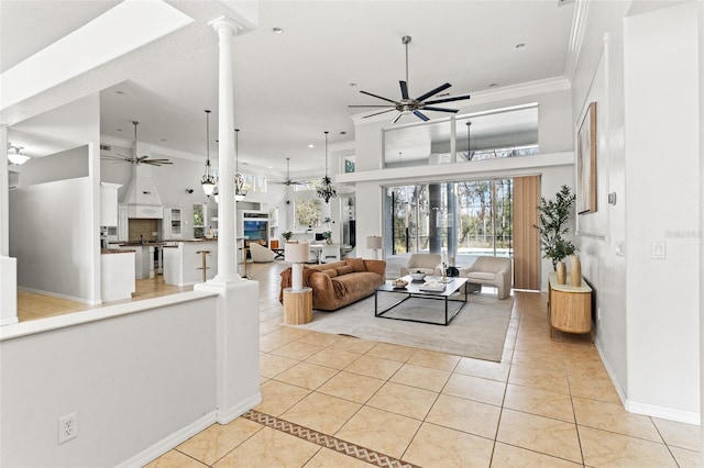 living room featuring ornate columns, crown molding, light tile patterned floors, ceiling fan, and a high ceiling