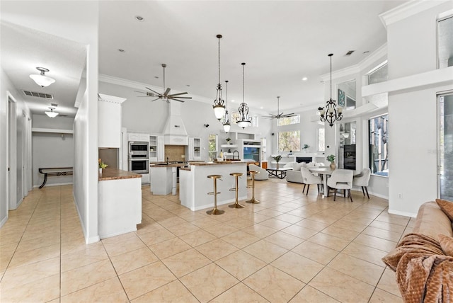 kitchen with white cabinetry, ceiling fan with notable chandelier, pendant lighting, and light tile patterned floors